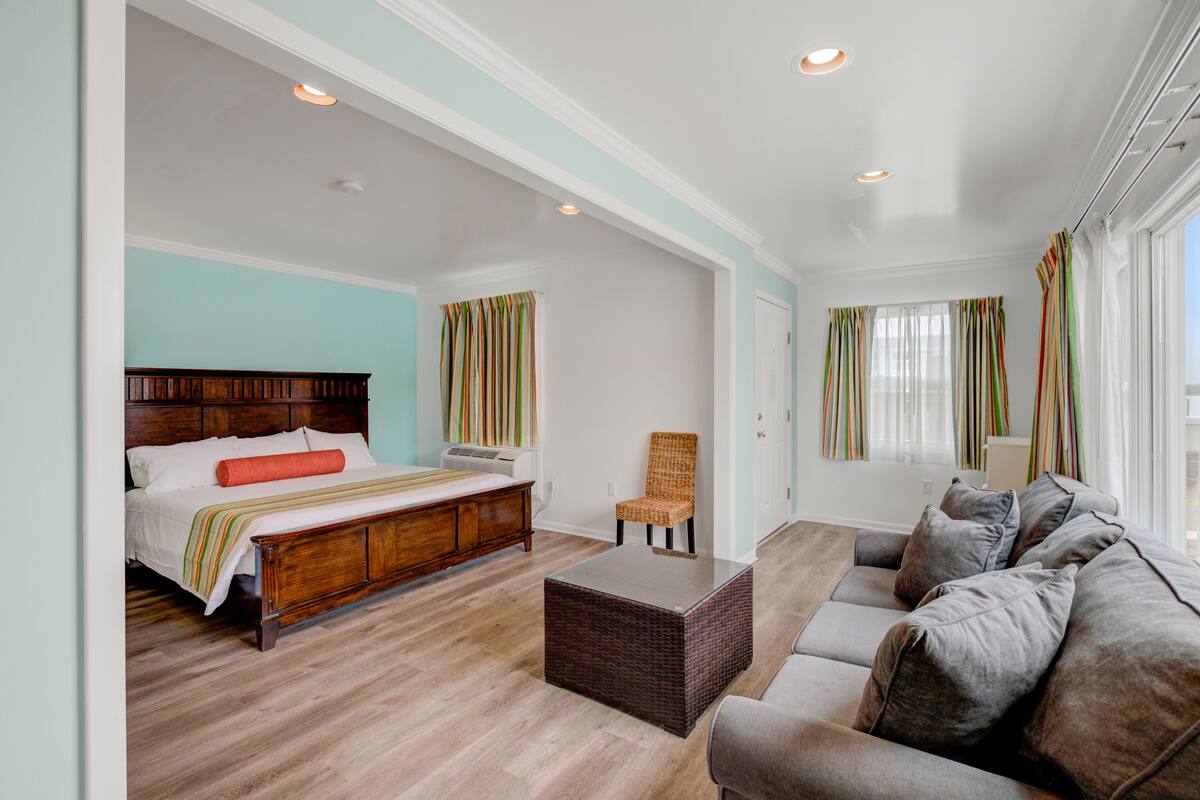 A bedroom with a wooden bed, a grey sofa, and a wicker coffee table.