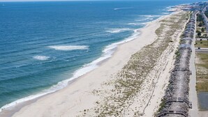 A coastal view with a beach, ocean, and a long train track running parallel to the shore.