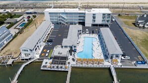 Vista aérea de un hotel con piscina, zona de estacionamiento y vista a la playa.