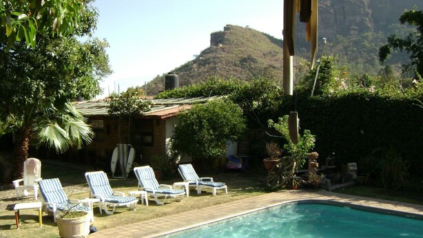 Piscina con sillones de descanso y montañas al fondo.