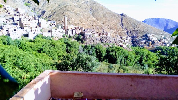 A terrace with a table and chairs, overlooking a mountainous village with traditional buildings. - Tanssi House (Asni)