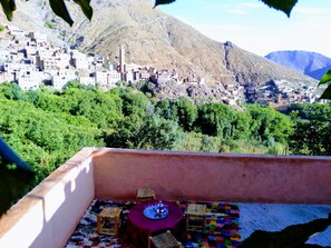 A terrace with a table and chairs, overlooking a mountainous village with traditional buildings. - Tanssi House (Asni)