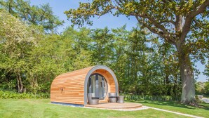 A small, wooden, semi-circular structure with a glass door and two chairs outside. - Bluebell Glamping Pod - sleeps 2 | Gold Award winning (Pickering)