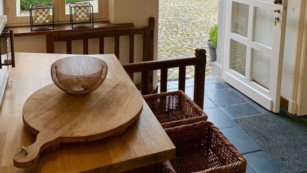 A cozy dining area with a wooden table, wicker baskets, and a hanging light fixture.