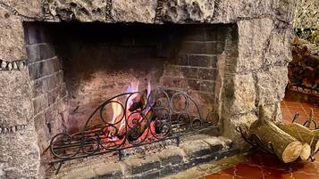 A stone fireplace with a metal fire screen and logs.