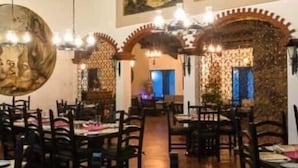 A restaurant with wooden beams, traditional decor, and tables set for dining. - Parador del Alma (Bocoyna)