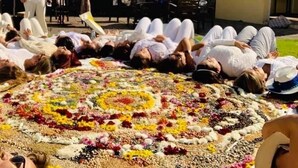 A group of people lying on the ground in a circle, surrounded by a floral arrangement. - Parador del Alma (Bocoyna)