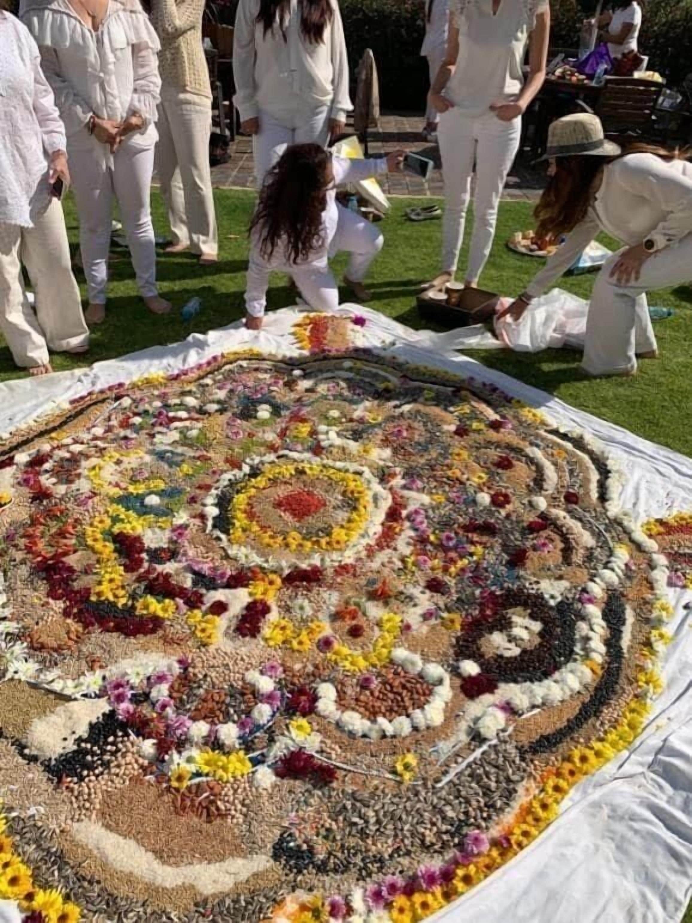 Un grupo de personas reunidas alrededor de una gran composición floral circular sobre un césped.