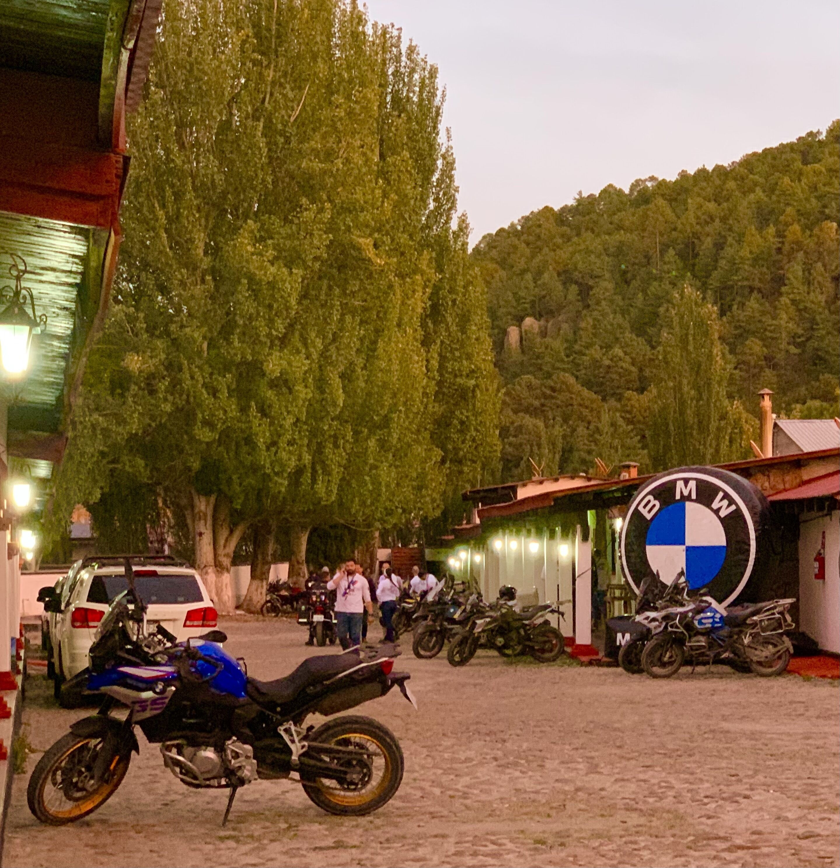 A parking area with motorcycles and a white car.