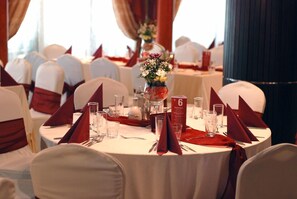 A round table with a white tablecloth, red napkins, and numbered place settings.