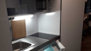 A compact kitchen with a built-in microwave, a stainless steel sink, and a drawer with a towel.