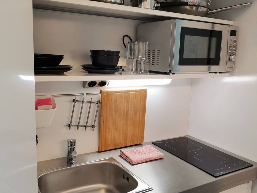 Una cocina moderna con electrodomésticos de acero inoxidable, incluyendo un microondas, estufa y fregadero.