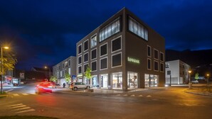 A modern building with multiple floors, large windows, and a visible sign for "Samikarp".