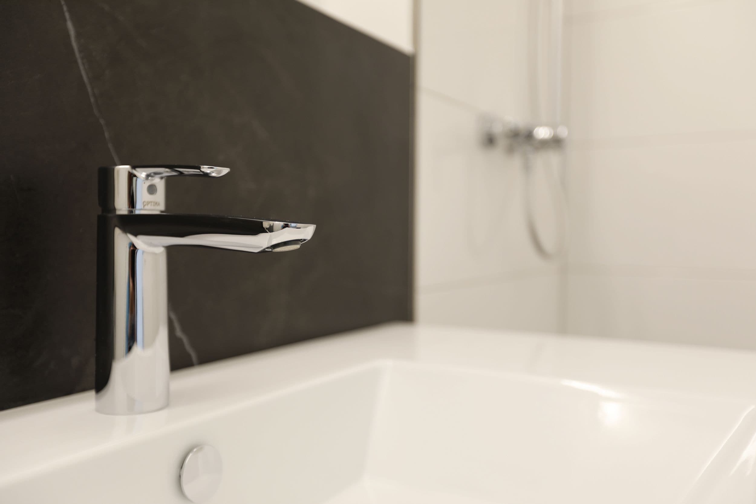 Ein modernes Badezimmer mit Chromarmatur und weißem Waschbecken.