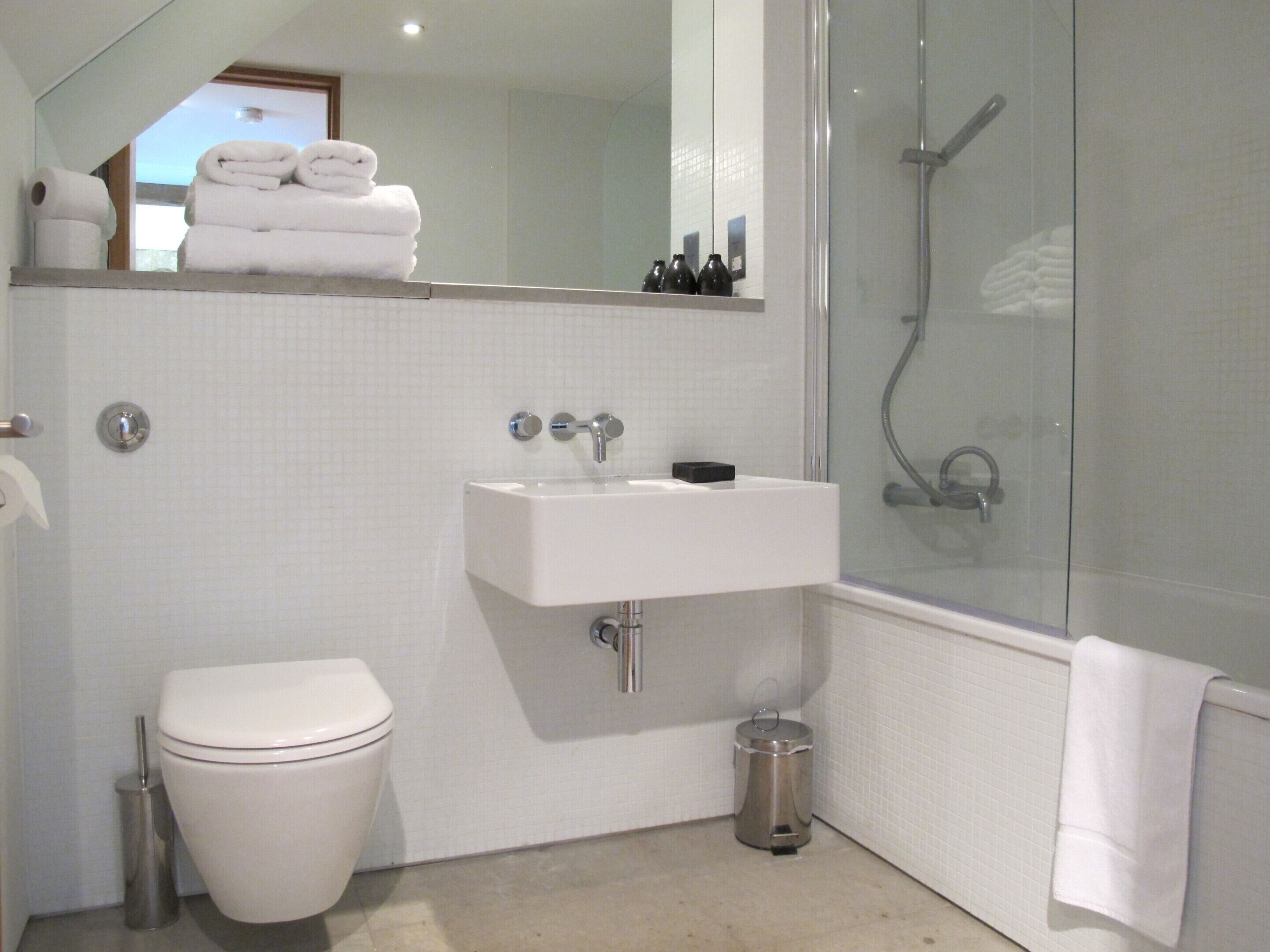 Une salle de bain moderne équipée de toilettes, d’un lavabo et d’une douche.