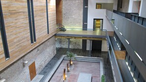 Un atrio de varios niveles con un patio central, paredes de piedra e iluminación moderna.