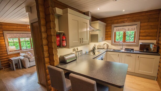 A modern kitchen with a central island, white cabinets, and a window with a view of greenery.