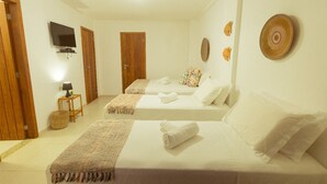 A hotel room with two beds, a TV, a lamp, and decorative wall art.