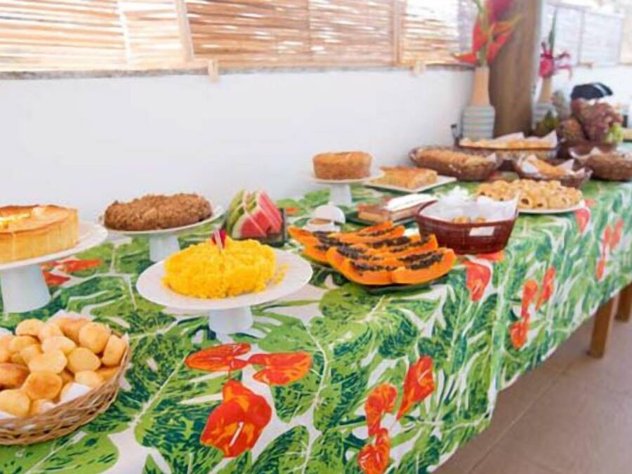 Een buffet met verschillende gerechten en een tafelkleed met tropisch thema.