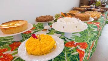 Una mesa de buffet con diferentes platos, incluyendo un guiso de arroz amarillo, un guiso de arroz blanco y varios postres.