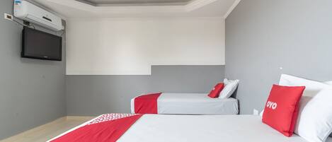 A hotel room with two beds, a flat-screen TV, and an air conditioning unit.