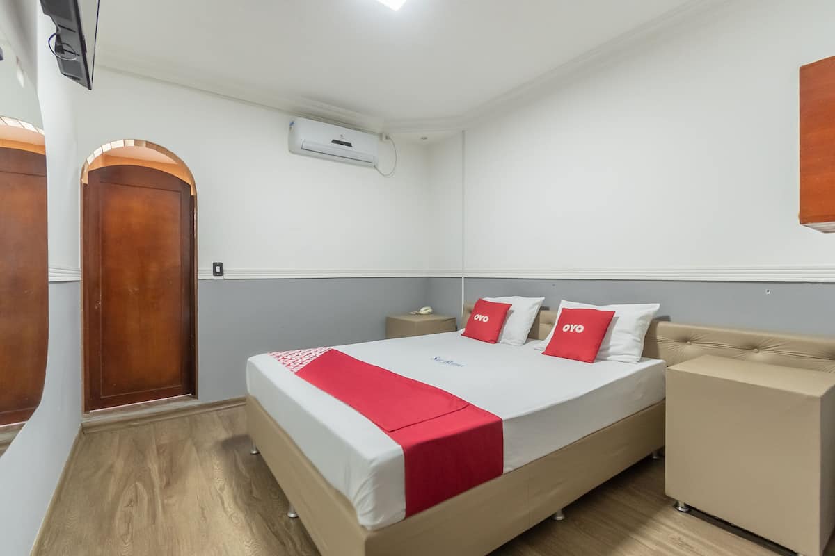 Une chambre d’hôtel avec un lit, une table de chevet et une armoire.