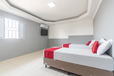 A bedroom with two beds, a TV, and a window.. OYO Hotel San Remo, São Paulo