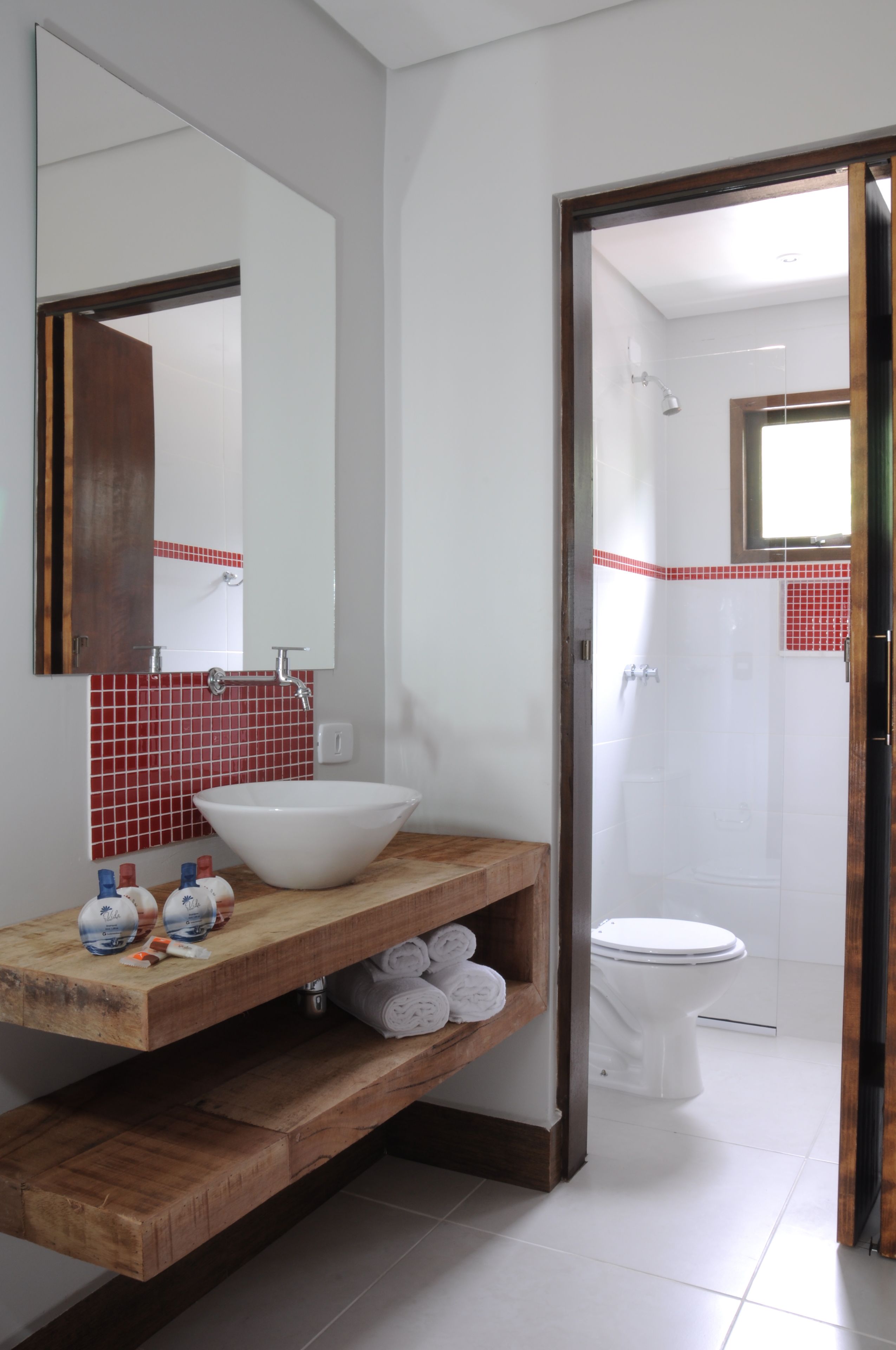 A bathroom with a wooden vanity, a large mirror, a white sink, and a shower area.