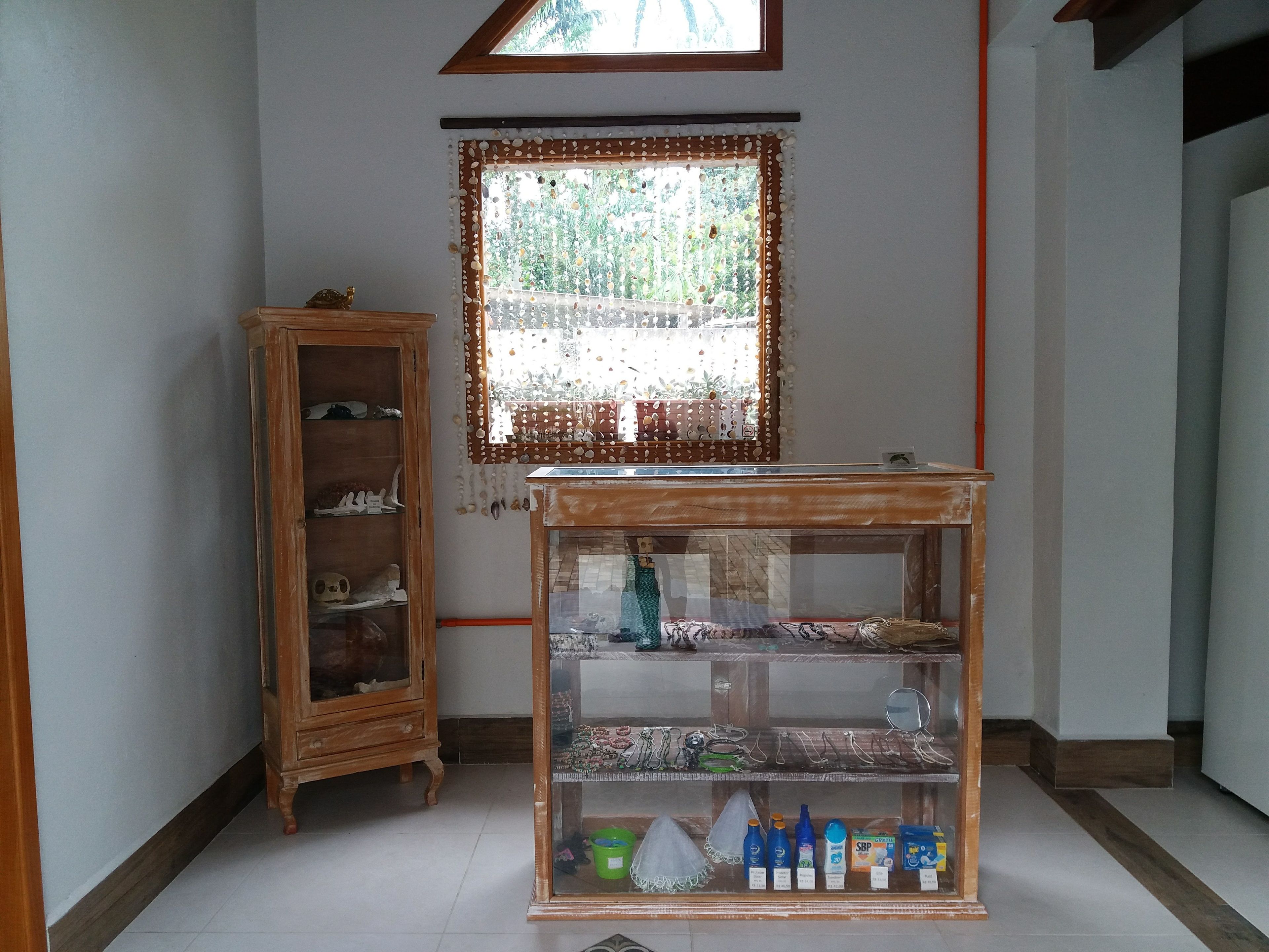 Una habitación con un armario de madera, una vitrina de cristal con varios objetos y una ventana con un marco decorativo.
