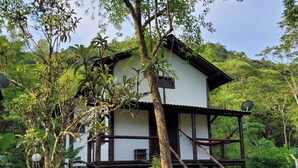 Ein zweistöckiges Holzhaus mit Balkon, umgeben von üppiger Vegetation.