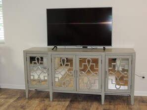 Entertainment unit features a flat-screen TV and three glass-fronted cabinets with intricate metal designs.