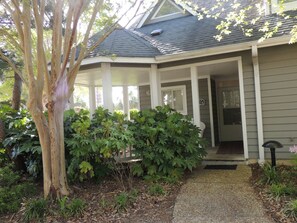 A house with a covered porch, a visible door, and a small garden area with various plants. - Windermere by the Sea #2A (Myrtle Beach)