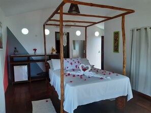 Un llit amb cortines i petxines de roses, i una disposició de tovalloles amb forma de cor.