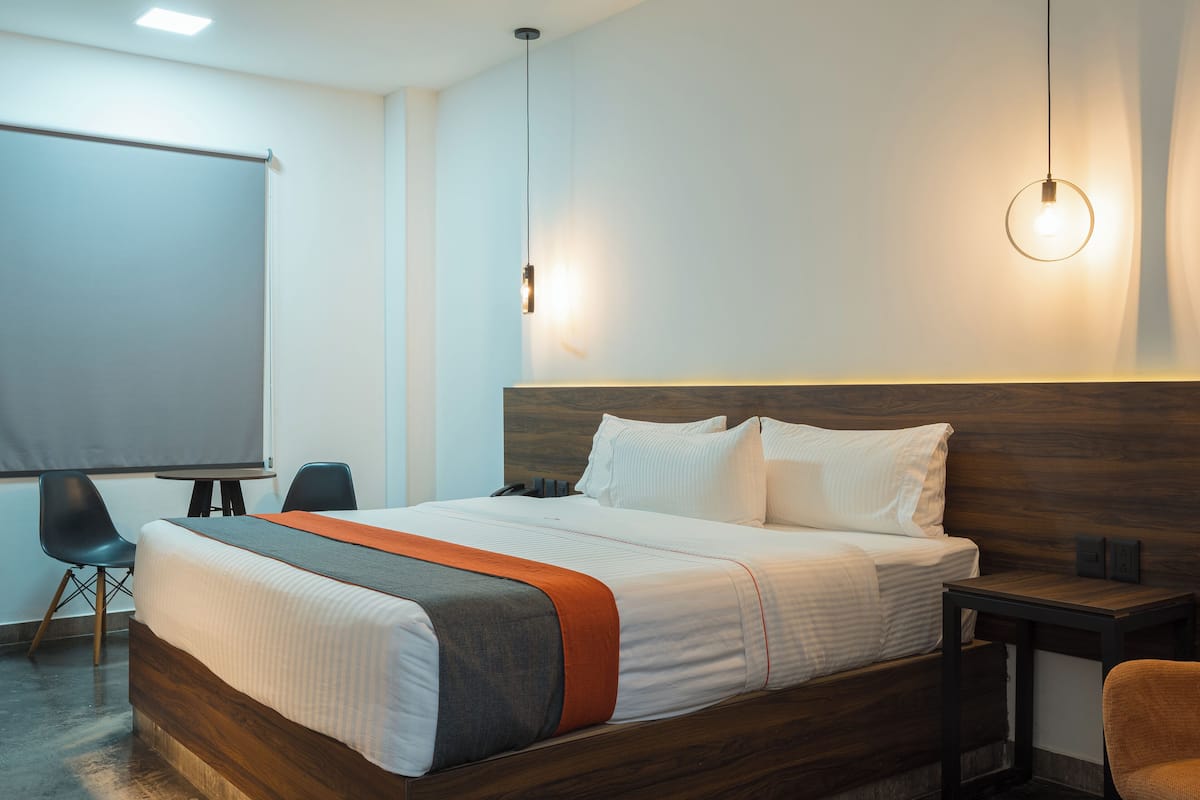 Een moderne hotelkamer met een groot bed, een bureau, een stoel en een projectiescherm.