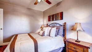 A bedroom with a bed, a nightstand, a lamp, and a ceiling fan. - Scenic Wonders Harmony Hilltop 3 Bd (Oakhurst)