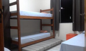 A bunk bed with a mattress and pillows, a small stool, and a table with a white tablecloth. - OUTHome - Espaço e Sabores (São Sebastião)