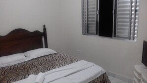 Un dormitorio con una cama de madera, ropa de cama con estampado de cebra, una ventana con persianas y un aparador blanco.