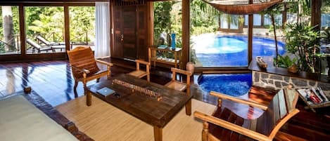 Un interior de madera con vista a la piscina, una mesa y sillas de madera.