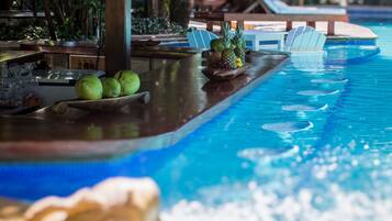 Un bar junto a la piscina con una bandeja de madera que contiene frutas y un coco.