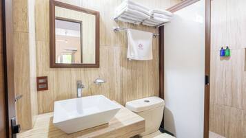 Un baño con lavamanos blanco, inodoro, espejo y toallero.