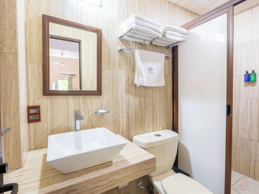Un baño con lavamanos blanco, inodoro, espejo y toallero.
