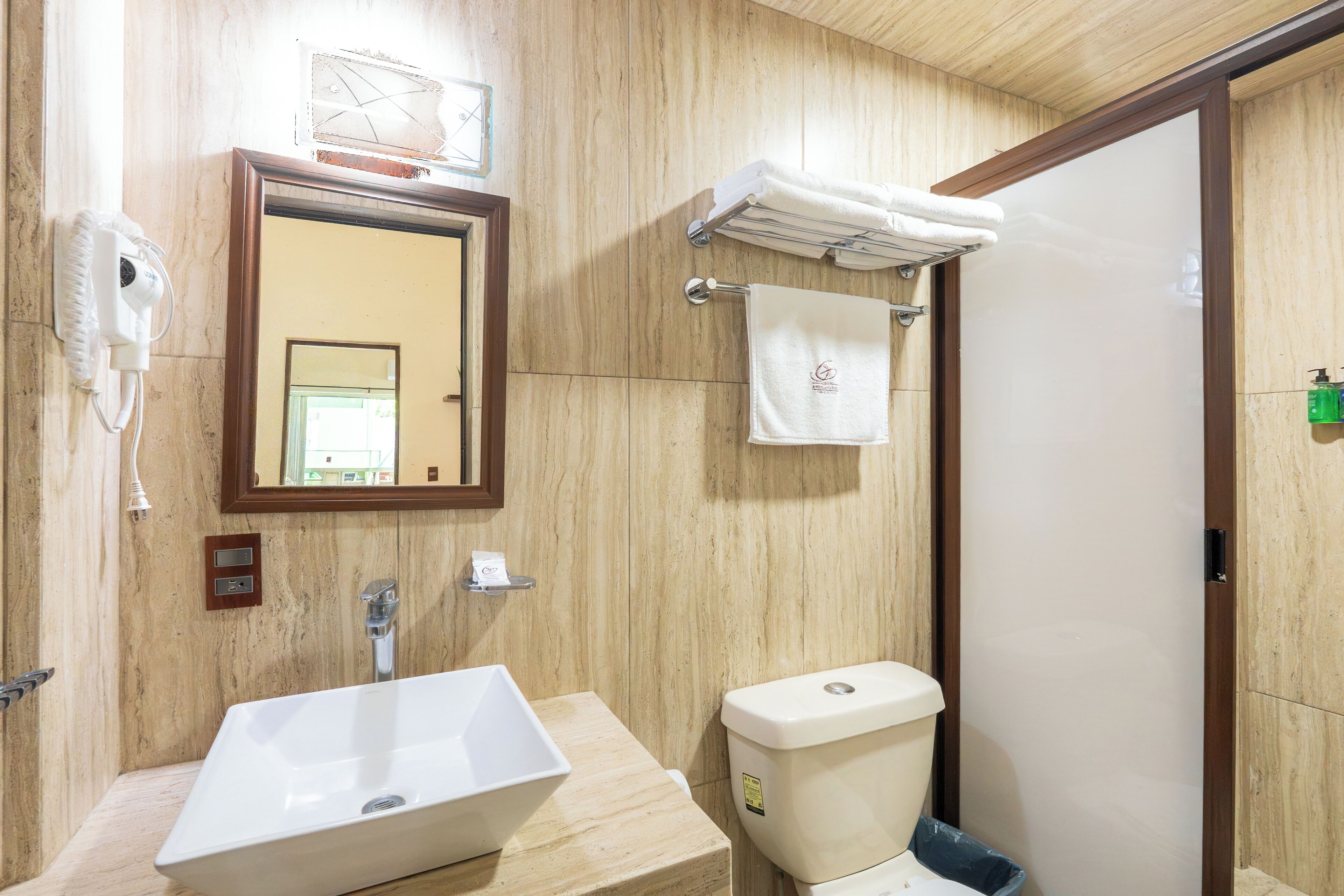 Une salle de bain avec un grand miroir, un lavabo, des toilettes et un porte-serviettes.