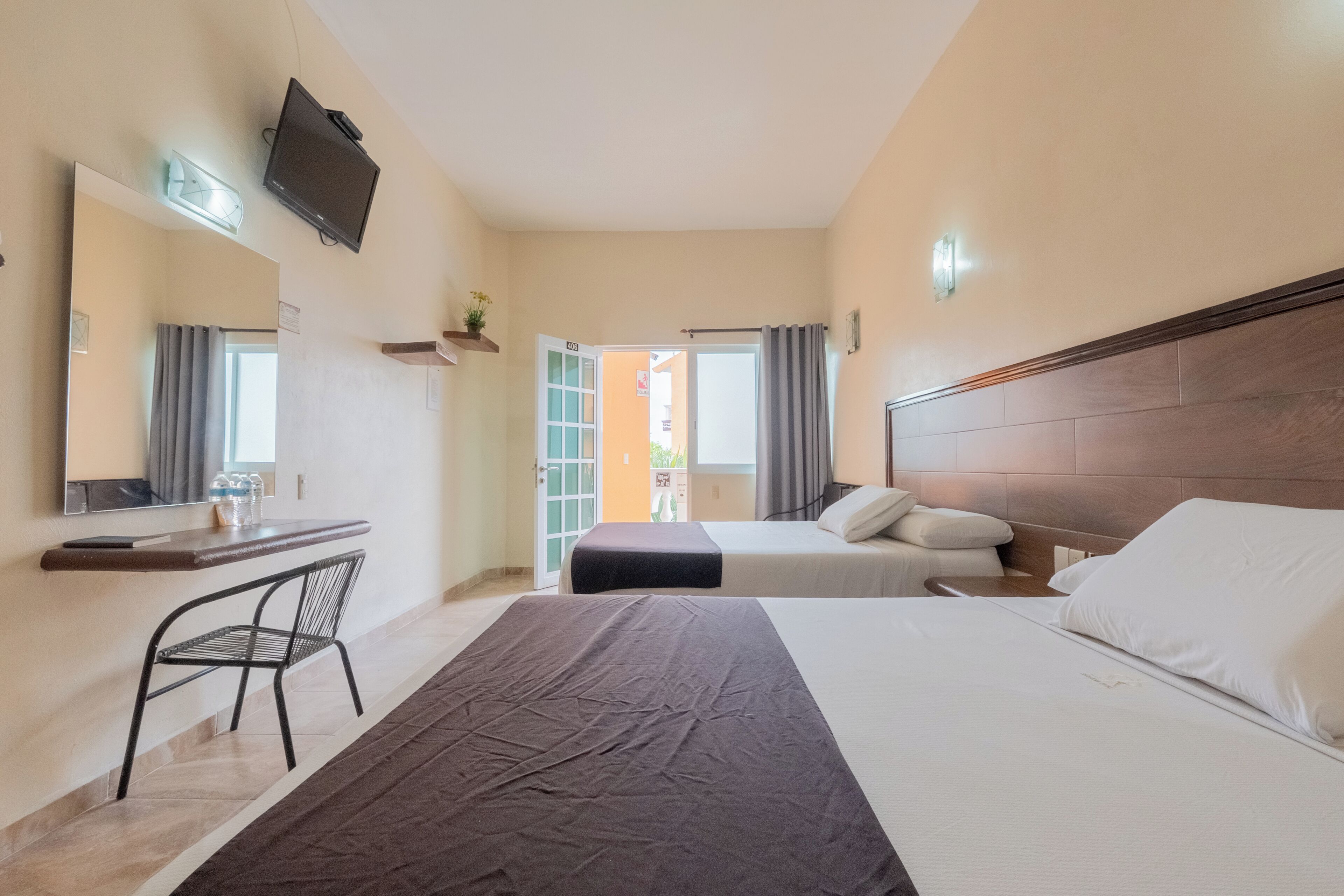 A hotel room with a bed, a desk, a chair, a television, and a bathroom door.