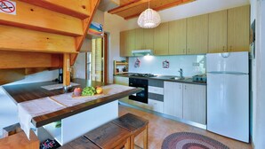Une cuisine avec des meubles de rangement en bois, une cuisinière à gaz, un évier et un réfrigérateur.