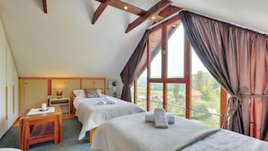 Une chambre avec deux lits, un bureau en bois et une fenêtre avec des rideaux.
