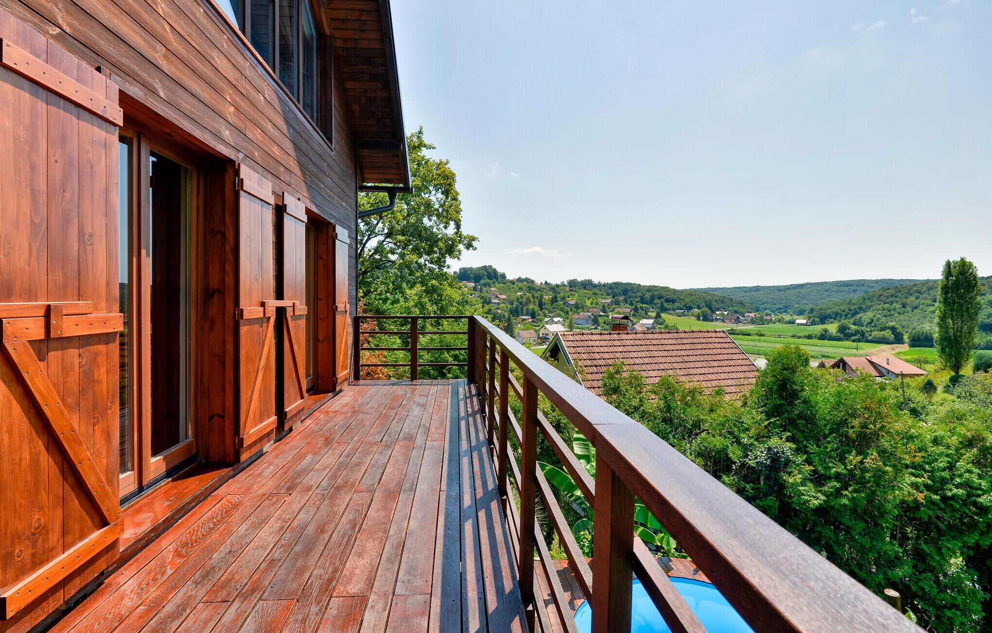 Ein Holzhaus mit einem Balkon mit Blick auf eine grüne Landschaft.