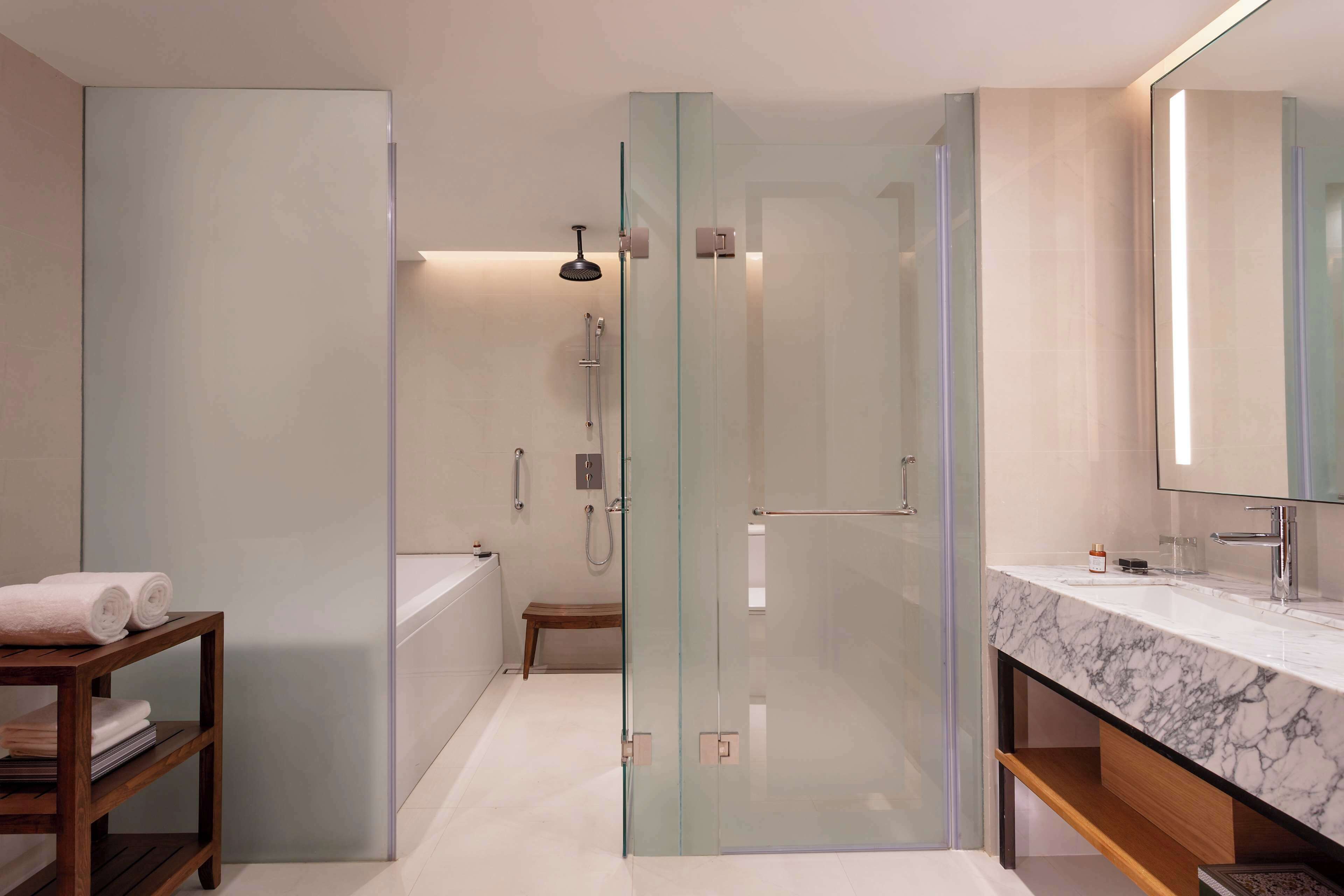 A modern bathroom with a glass-enclosed shower, a marble sink, and a wooden vanity.