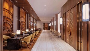 A hotel lobby with a long reception desk, multiple chairs, and a patterned wall design. - Hyatt Regency Dharamshala Resort (Dharamshala)