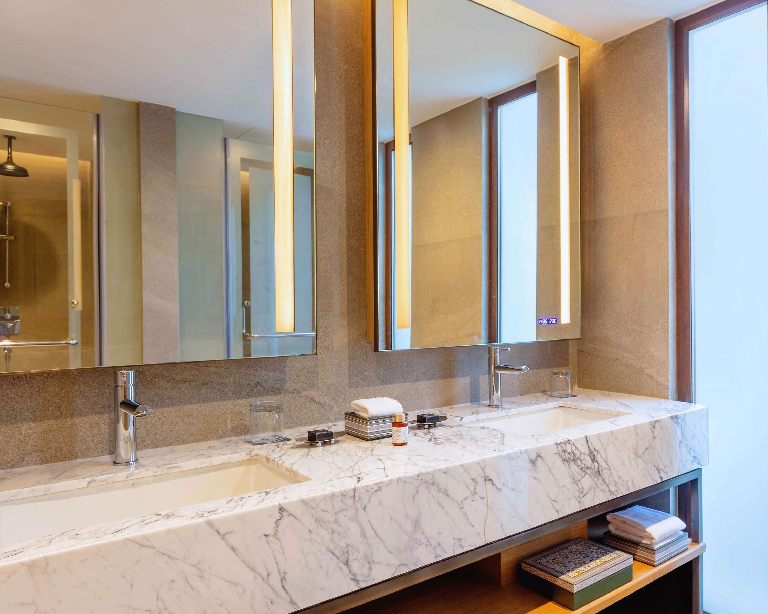 A modern bathroom with two sinks, large mirrors, and a marble countertop.