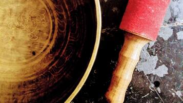 A wooden bowl with a red handle on a textured surface.
